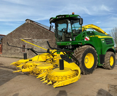 Översiktsbild av John Deere 8400 hakselaar met maïsbek en grasopraper